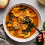 Creamy Tortellini Soup in rustic bowl with spinach and tomato broth