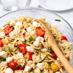 Caprese Pasta Salad in a bowl with basil and tomatoes