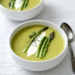 Creamy Asparagus Soup in a bowl with coconut milk and parsley