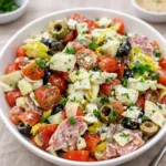 A colorful bowl of Antipasto Salad with tomatoes, salami, and olives.