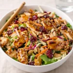 A vibrant bowl of Asian Chicken Cranberry Salad with chicken and nuts.