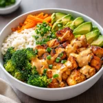 Bang bang chicken bowl with broccoli topped with sesame seeds