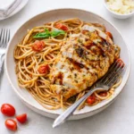 A skillet of Best Bruschetta Chicken Pasta with fresh tomatoes and basil