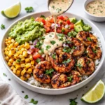 A vibrant Grilled Shrimp Bowl with Avocado topped with creamy sauce.