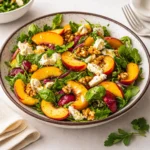 Fresh Irresistible Peach Salad with feta and pecans on a wooden table