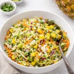 A bowl of fresh Pineapple Coleslaw with lime and pineapple on the side
