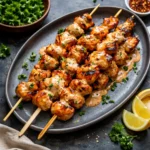 Bang Bang Chicken Skewers on a white platter with green onions