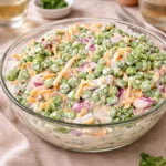 Easy English Pea Salad in a white bowl with bacon and cheese