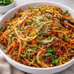 Vibrant Rainbow Carrot Sesame Salad in a ceramic bowl garnished with sesame seeds