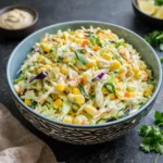 Spicy Jalapeno Corn Coleslaw in a white bowl on a wooden table